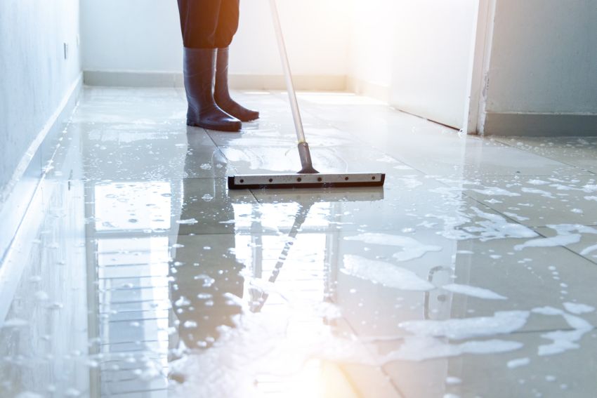 Janitor mopping a wet office floor in a hallway, business cleaning service role
